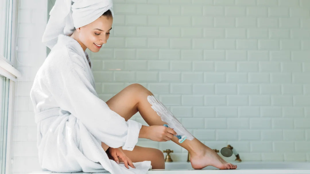 A woman in a bathrobe relaxes on the edge of a bathtub, surrounded by Tend Skin products for skincare.